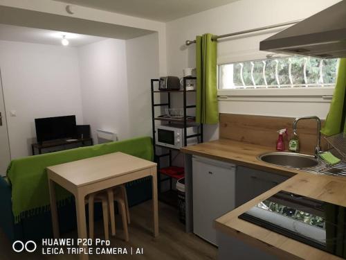 a small kitchen with a table and a green couch at Le Cyprès in Saint-Mitre-les-Remparts