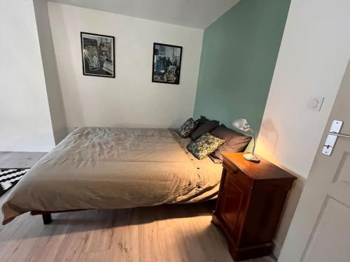 een slaapkamer met een bed en een nachtkastje met een lamp bij Grande chambre chez l'artiste-peintre in La Réole