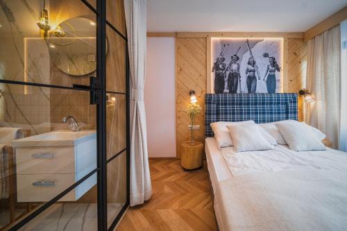 a bedroom with a bed and a sink and a mirror at GORSKI RESORT Lux Apartments Jacuzzi & Sauna in Poronin