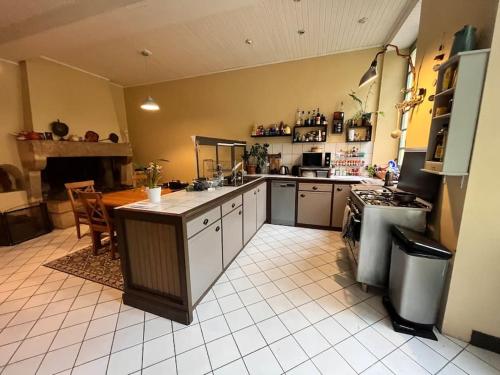 a large kitchen with a counter and a stove at Grande chambre chez l'artiste-peintre in La Réole