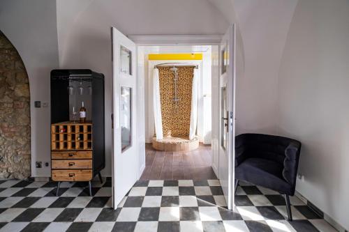 a hallway with a black chair and a checkerboard floor at Kníže Ferdinand Apartments in Mikulov
