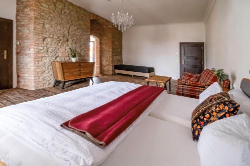 a bedroom with a large white bed with a red blanket on it at Kníže Ferdinand Apartments in Mikulov