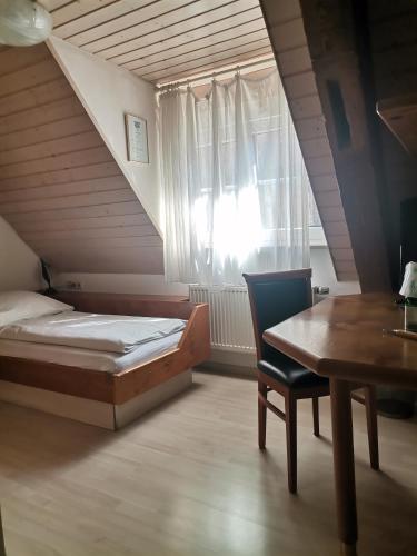 Un dormitorio con una cama y una mesa y una ventana. en Engelhof, en Weilheim an der Teck