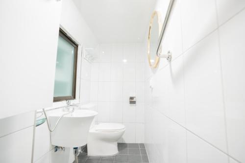 a white bathroom with a toilet and a window at Huayuanhouse HQ in hongdae in Seoul