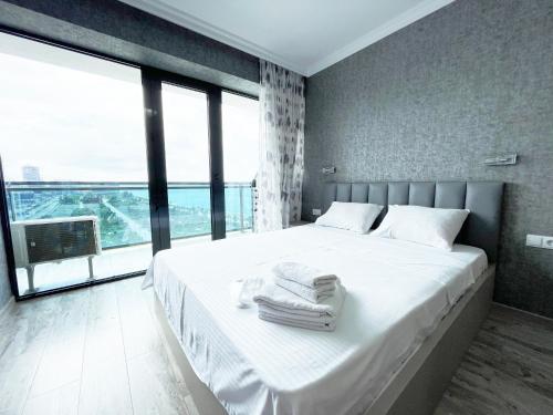 a bedroom with a large white bed with a large window at Batumi Beach in Batumi