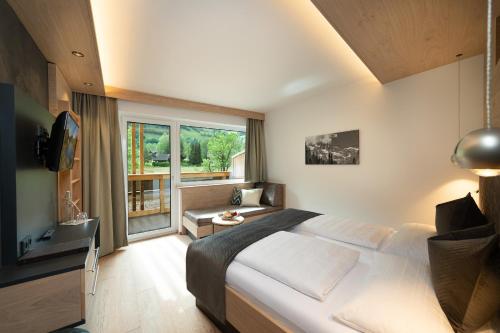 a bedroom with a large bed and a large window at Hotel Alpina in Rauris