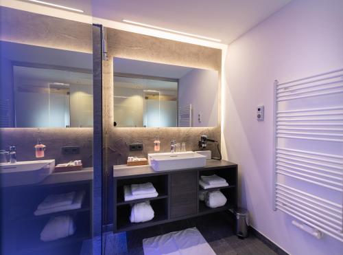 a bathroom with two sinks and a large mirror at Hotel Alpina in Rauris