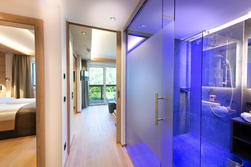 a bathroom with a walk in shower next to a bedroom at Hotel Alpina in Rauris