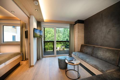 a living room with a couch and a large window at Hotel Alpina in Rauris