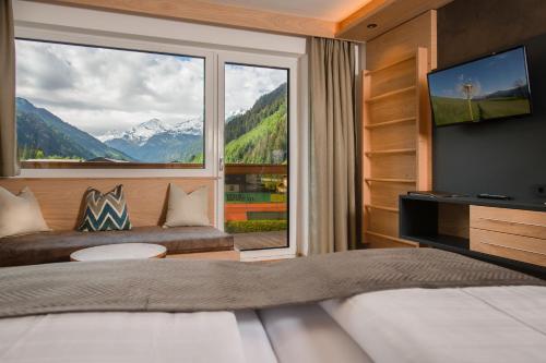 a bedroom with a bed and a large window at Hotel Alpina in Rauris