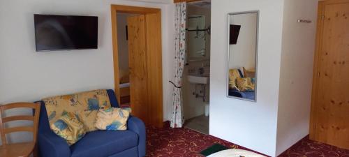 a living room with a blue chair and a mirror at Pension Backstuba in Partenen