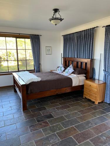 a bedroom with a large bed with blue curtains at Bicheno getaway for two in Bicheno