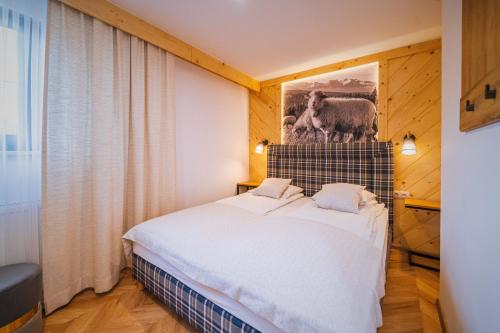 a bedroom with a bed and a picture of a sheep at GORSKI RESORT Lux Apartments Jacuzzi & Sauna in Poronin