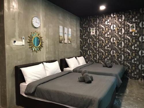 a bedroom with two beds and a clock on the wall at Hotel EC KIP Sentral KLIA 1 - KLIA 2 in Sepang
