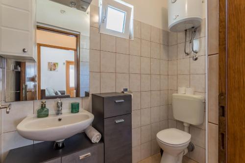 a bathroom with a sink and a toilet and a mirror at Apartments Drago Kovačić in Omiš