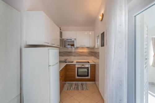 a kitchen with white cabinets and a white refrigerator at Apartments Drago Kovačić in Omiš