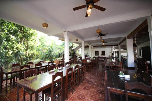 a restaurant with tables and chairs and a ceiling fan at Vangsavath Hotel in Luang Prabang