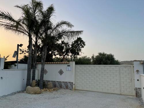 a white fence with a palm tree in front of it at Relais Dea Degli Ulivi in Agrigento