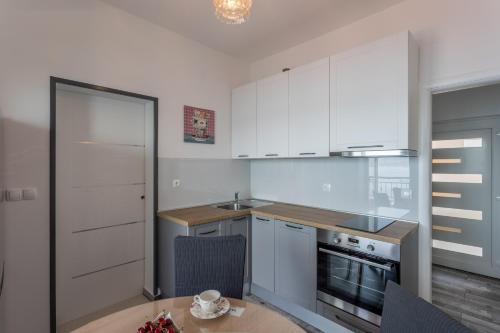 a kitchen with white cabinets and a wooden table at Apartments Drago Kovačić in Omiš