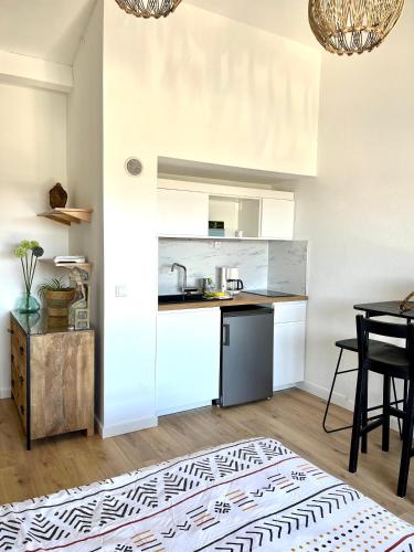 une cuisine avec des armoires blanches et une table avec des chaises dans l'établissement coup de cœur, à Grimaud