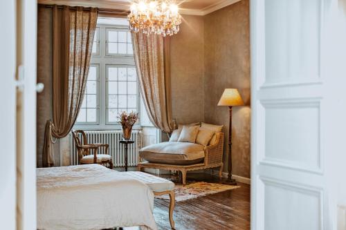 una camera con letto, sedia e lampadario a braccio di Château de Crazannes a Crazannes