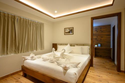 a bedroom with a bed with white sheets and a window at Chithara Comforts in Udupi