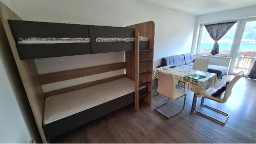 een kleine kamer met een stapelbed en een tafel bij Gemütliche Seeblickwohnung Lara in Sattendorf