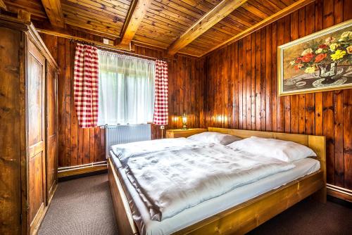 a bedroom with a bed in a wooden room at Chata Partizán in Liptovský Ján