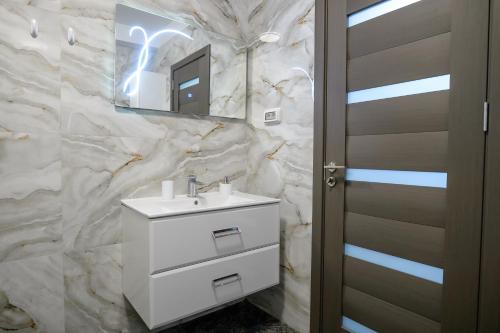 ein Badezimmer mit einem weißen Waschbecken und einem Spiegel in der Unterkunft Apartament Aleyna Eforie Nord in Eforie Nord