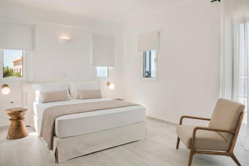 a white bedroom with a bed and a chair at Lourdas White Villa in Kefallonia