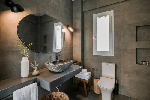 a bathroom with a sink and a toilet and a mirror at Lourdas White Villa in Kefallonia
