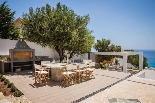 a patio with a table and chairs and a fireplace at Lourdas White Villa in Kefallonia
