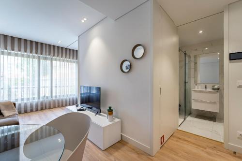uma sala de estar com uma mesa de vidro e uma televisão em Antas Park Apartment no Porto