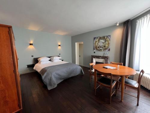 um quarto de hotel com uma cama e uma mesa em Le Petit Château em Baye