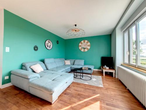 a living room with a blue couch and a tv at Au Mont Chez Vous #Jacuzzi et Vue Mont-St-Michel# in Huisnes-sur-Mer