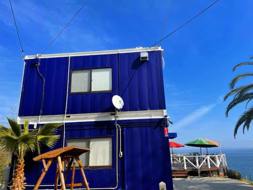 a blue house on the beach next to the ocean at 1棟貸し tbtランド 定員最大12名 in Shodoshima
