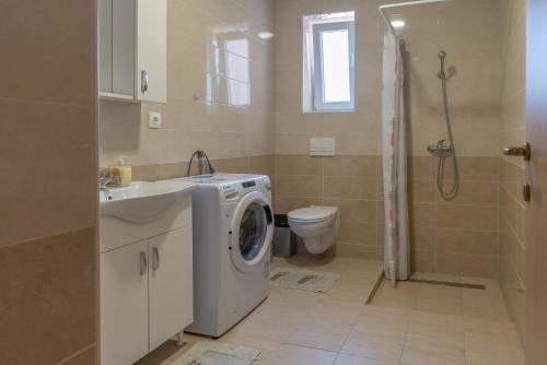 a bathroom with a washing machine and a toilet at Apartmani Kržak in Nin