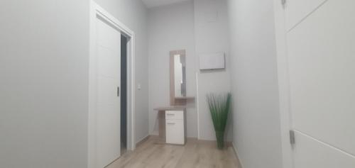 a white hallway with a table and a vase at Apartamentos Las trece llaves Jacuzzi bajo reserva in Merida