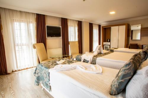 a hotel room with three beds and a television at Bursa Palas Hotel in Bursa
