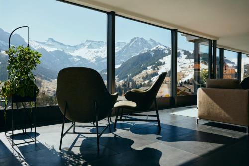 a room with two chairs and a view of mountains at The Cambrian in Adelboden