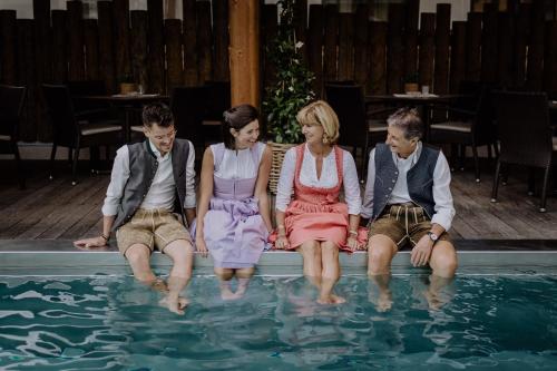 a group of people sitting next to a swimming pool at Hotel Sonnegg in Saalbach Hinterglemm