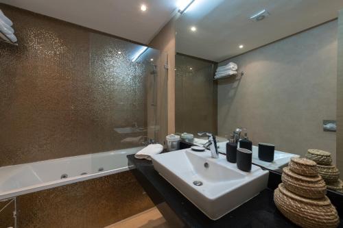 a bathroom with a sink and a mirror and a tub at Appartement 300m2 vue sur océan Prestigia - Plage des nations in Salé