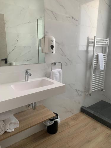 a white bathroom with a sink and a mirror at Hotel Don Pepo in Lobón