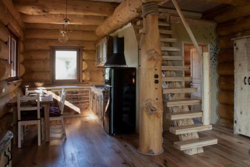 a kitchen with a stove and a staircase in a log cabin at Brunarica Biopark -Log house Biopark in Grosuplje
