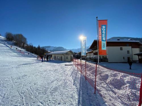 a snow covered slope with a fence and a building at Ferienwohnung Schnaitl in Maria Alm am Steinernen Meer