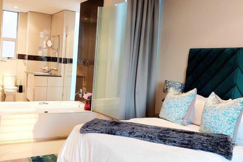 a bedroom with a bed and a bathroom with a tub at Queys 401 in Durban