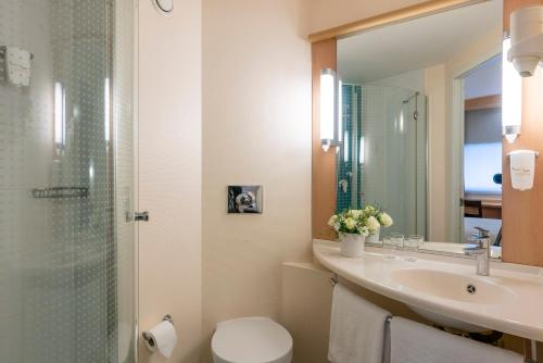 a bathroom with a toilet, sink, and mirror at Ibis Izmir Alsancak in İzmir