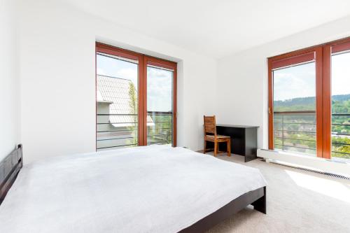 a white bedroom with a large bed and windows at Vila Sluneční stráň in Svoboda nad Úpou
