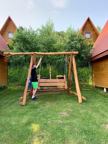 a woman is playing on a swing in a yard at Domki nad Soliną CZARNY KOT 509-797-777 in Solina