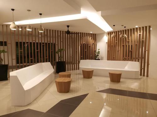 a lobby with a white couch and wooden stools at Preferred30 3R2B 7pax Meritus Perai in Perai